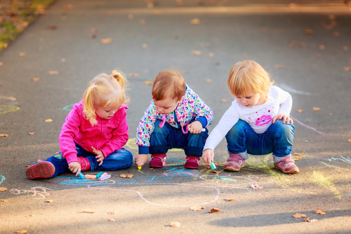 Toddlers Drawing Outside with a chalk on a sidewalk