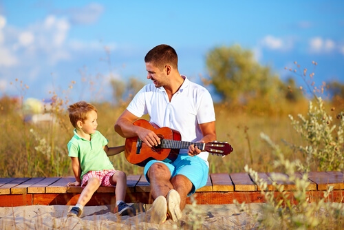 Father playing guitar to his child unschooling